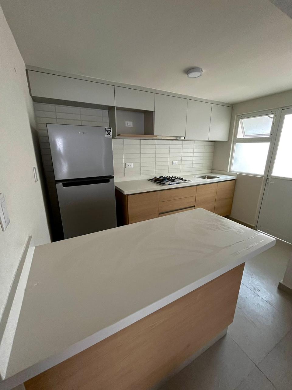Cocina compacta en blanco con isla de mármol para departamento